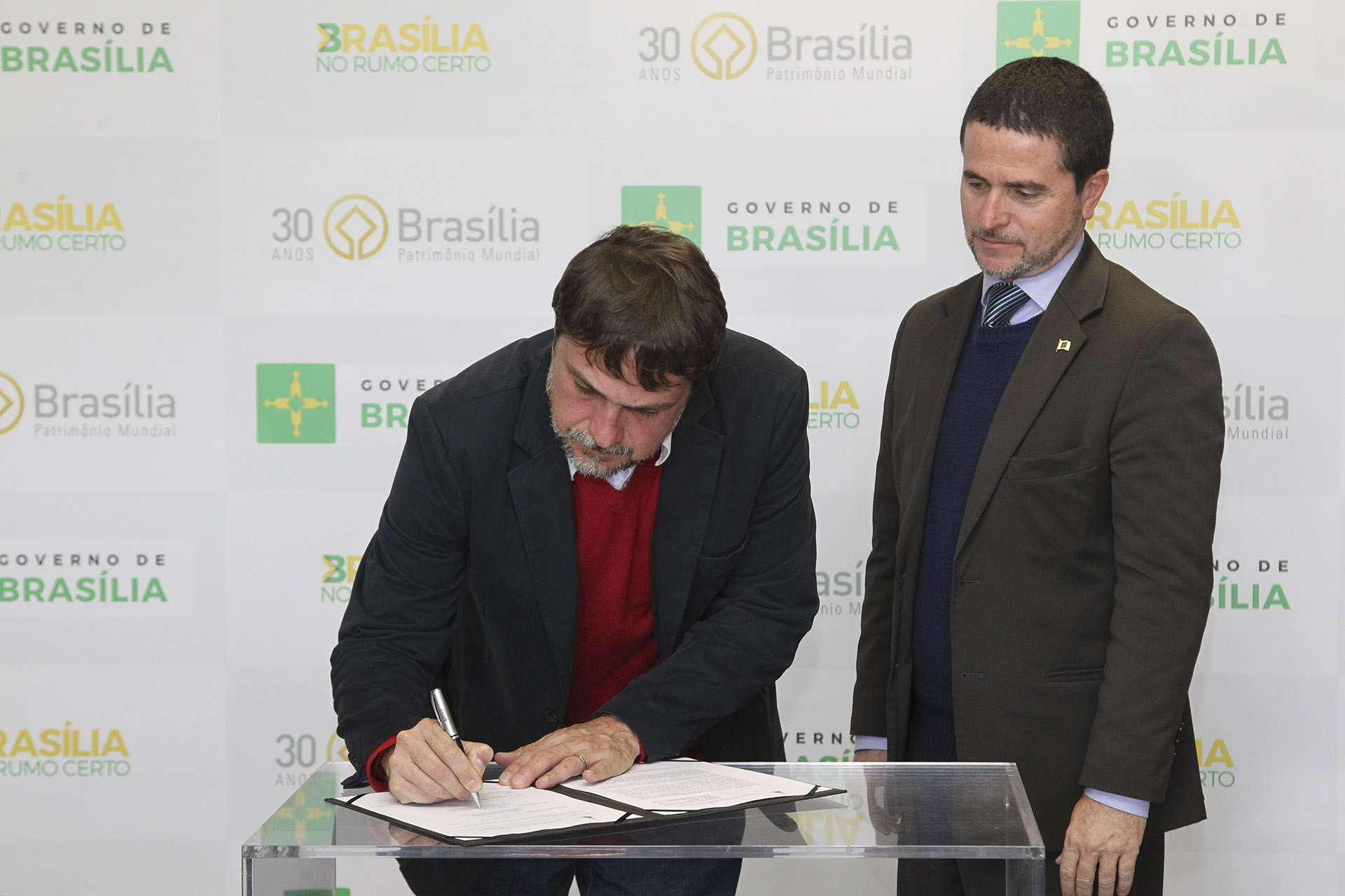 O presidente do Instituto de Arquitetos do Brasil (IAB-DF), Célio Melis Júnior, assina o contrato ao lado do chefe da Casa Civil em exercício, Fábio Pereira.