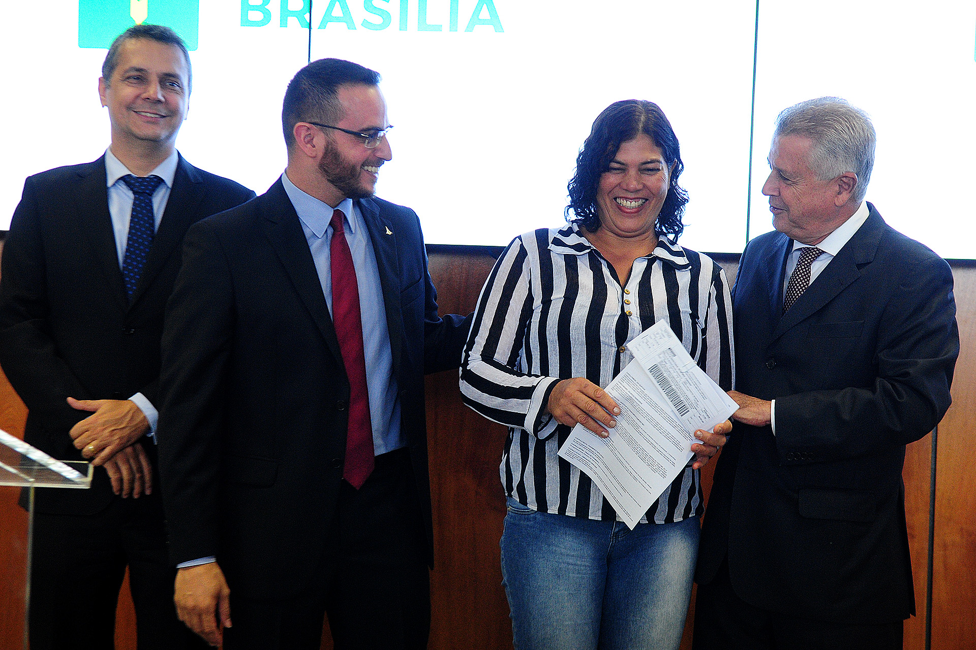 O presidente do BRB, Vasco Cunha Gonçalves, o secretário adjunto do Trabalho, Thiago Jarjour, e o governador Rodrigo Rollemberg, entregam em a carta de crédito para a microempresária Dorcília de Moraes.